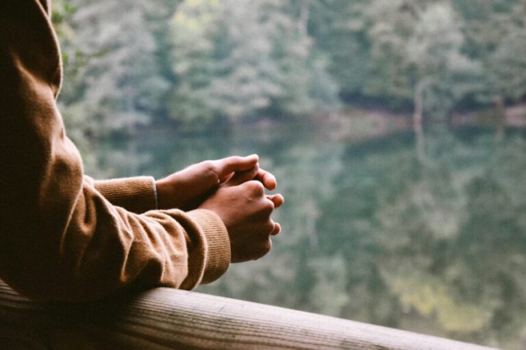 Person with folded hands looking outside